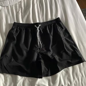 Men’s black bathing suit shorts with netting still inside.